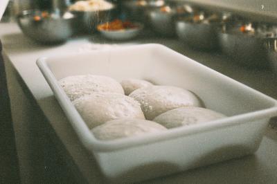 Un homme retire une pizza du four à l'aide d'une pelle, accompagné d'une femme souriante dans une cuisine moderne.