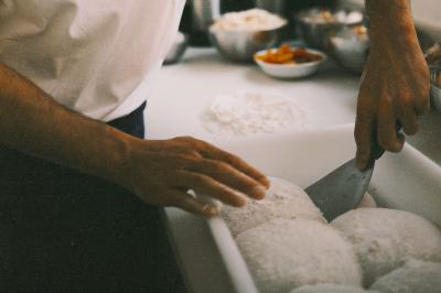 Un homme retire une pizza du four à l'aide d'une pelle, accompagné d'une femme souriante dans une cuisine moderne.