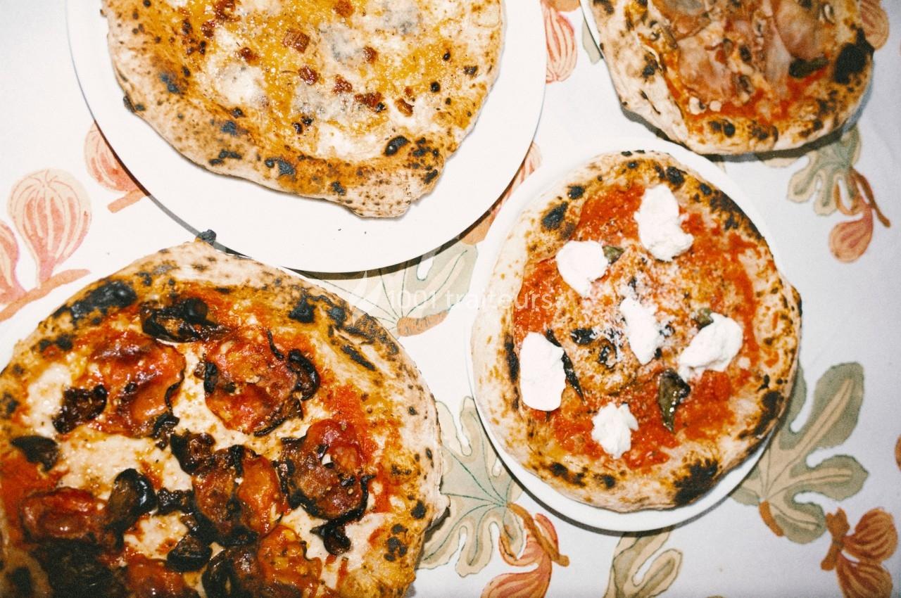 Quatre pizzas variées sur une table avec une nappe à motifs floraux.