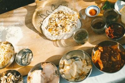 Un homme retire une pizza du four à l'aide d'une pelle, accompagné d'une femme souriante dans une cuisine moderne.