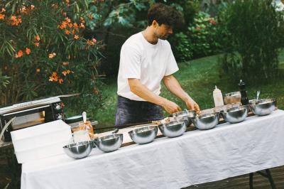 Un homme retire une pizza du four à l'aide d'une pelle, accompagné d'une femme souriante dans une cuisine moderne.
