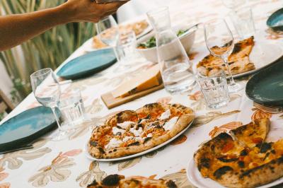Un homme retire une pizza du four à l'aide d'une pelle, accompagné d'une femme souriante dans une cuisine moderne.