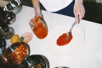 Un homme retire une pizza du four à l'aide d'une pelle, accompagné d'une femme souriante dans une cuisine moderne.
