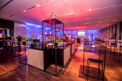 Groupe de personnes en tenue professionnelle réunies lors d'un événement dans une grande salle éclairée.