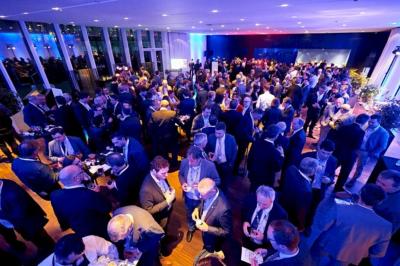 Groupe de personnes en tenue professionnelle réunies lors d'un événement dans une grande salle éclairée.