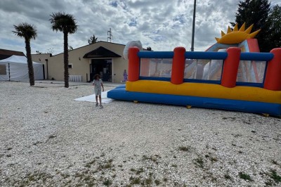 Miniature Location salle Gien (Loiret) - Le Prestigia #16 Structure gonflable colorée sur un sol gravillonné, avec un enfant à proximité et un bâtiment en arrière-plan.