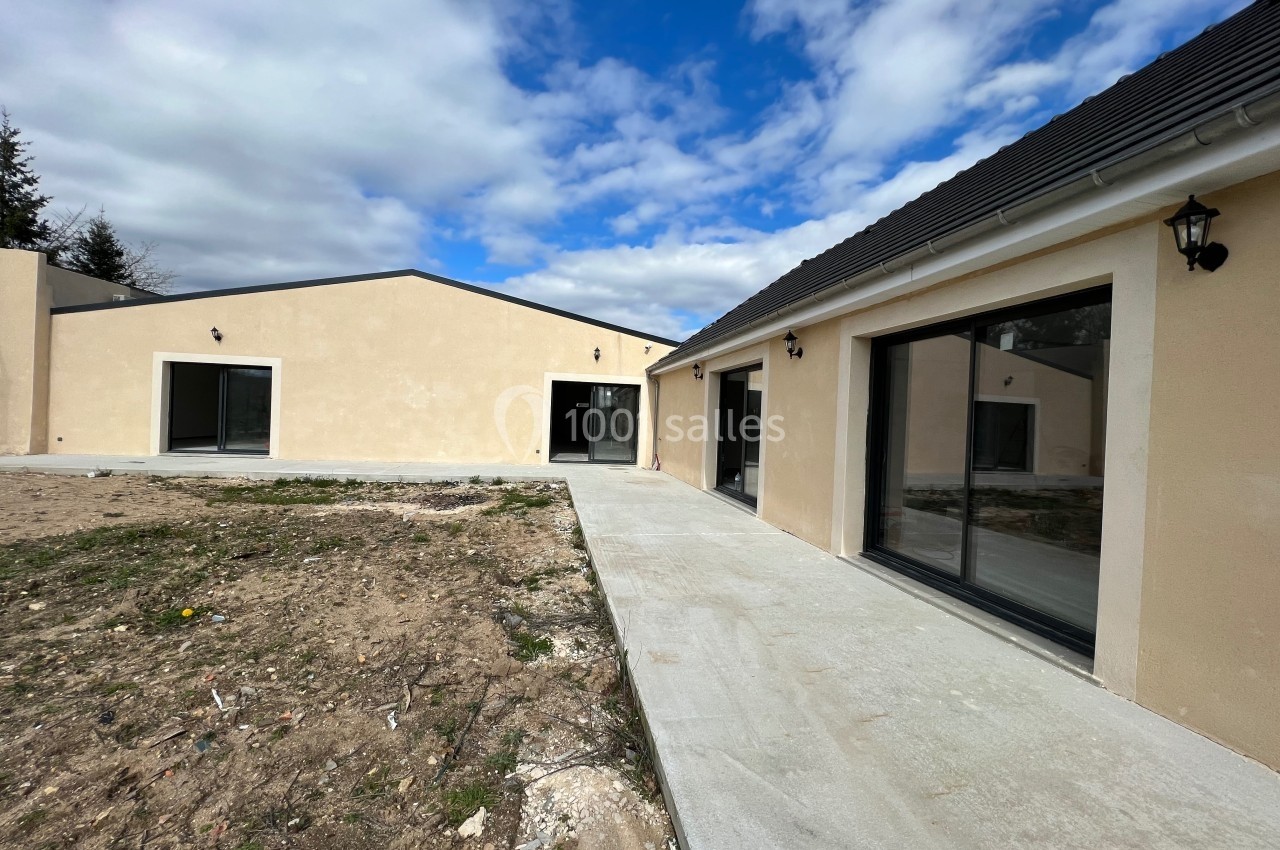 Maisons modernes de plain-pied avec façades claires, grandes baies vitrées et allée en béton sous un ciel partiellement…