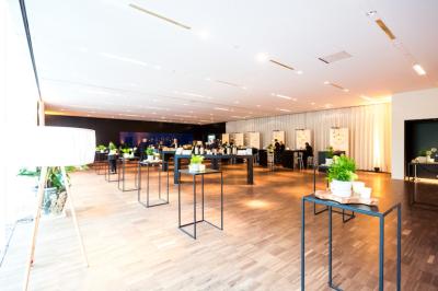 Salle de conférence vide avec rangées de chaises noires, éclairage bleu et une table haute sur une estrade.