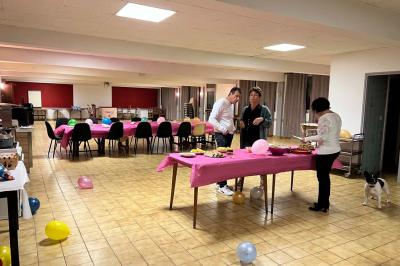 Cuisine moderne avec meubles en bois clair, électroménagers, table blanche et chaises, lave-linge et sèche-linge visibles.
