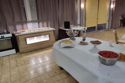 Cuisine moderne avec meubles en bois clair, électroménagers, table blanche et chaises, lave-linge et sèche-linge visibles.