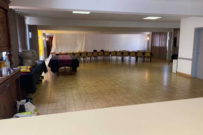 Cuisine moderne avec meubles en bois clair, électroménagers, table blanche et chaises, lave-linge et sèche-linge visibles.