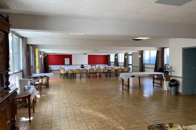 Cuisine moderne avec meubles en bois clair, électroménagers, table blanche et chaises, lave-linge et sèche-linge visibles.