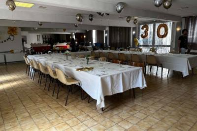 Cuisine moderne avec meubles en bois clair, électroménagers, table blanche et chaises, lave-linge et sèche-linge visibles.