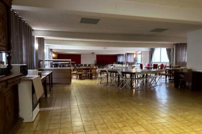 Cuisine moderne avec meubles en bois clair, électroménagers, table blanche et chaises, lave-linge et sèche-linge visibles.