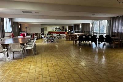 Cuisine moderne avec meubles en bois clair, électroménagers, table blanche et chaises, lave-linge et sèche-linge visibles.