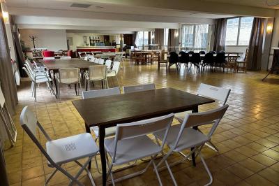 Cuisine moderne avec meubles en bois clair, électroménagers, table blanche et chaises, lave-linge et sèche-linge visibles.