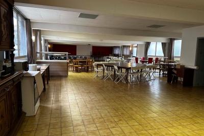 Cuisine moderne avec meubles en bois clair, électroménagers, table blanche et chaises, lave-linge et sèche-linge visibles.