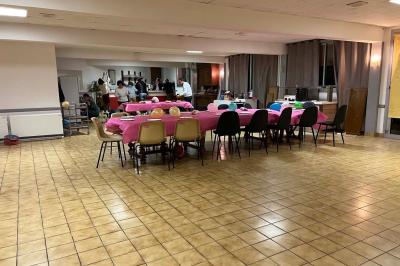 Cuisine moderne avec meubles en bois clair, électroménagers, table blanche et chaises, lave-linge et sèche-linge visibles.