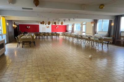 Cuisine moderne avec meubles en bois clair, électroménagers, table blanche et chaises, lave-linge et sèche-linge visibles.