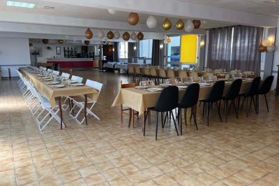 Cuisine moderne avec meubles en bois clair, électroménagers, table blanche et chaises, lave-linge et sèche-linge visibles.