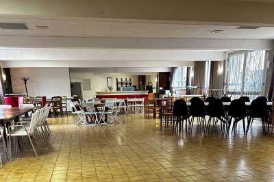 Cuisine moderne avec meubles en bois clair, électroménagers, table blanche et chaises, lave-linge et sèche-linge visibles.