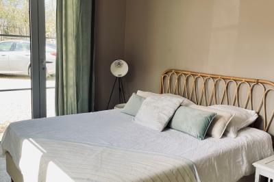 Façade d'une maison en pierre avec terrasse ensoleillée, chaises longues et pots de fleurs sur un sol pavé clair.