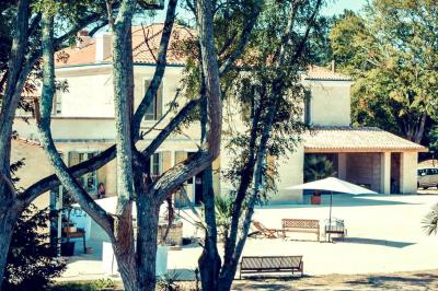 Tentes blanches installées dans une prairie verdoyante entourée d'arbres sous un ciel bleu clair.