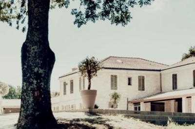 Tentes blanches installées dans une prairie verdoyante entourée d'arbres sous un ciel bleu clair.