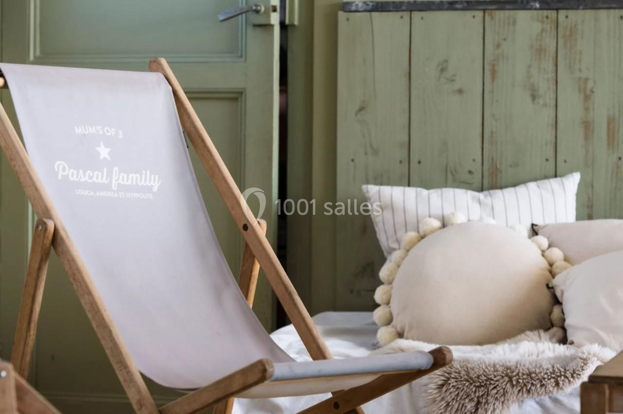 Chaise longue en bois avec tissu imprimé, placée dans un intérieur cosy avec coussins et mobilier en bois vert.