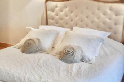 Tentes blanches installées dans une prairie verdoyante entourée d'arbres sous un ciel bleu clair.