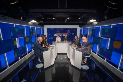 Miniature Agence Ilago #5 Des personnes échangent dans un espace d'exposition intérieur avec des stands et une structure métallique visible en arrière…