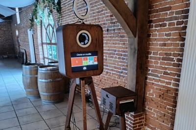 Borne photo en bois sur trépied avec un anneau lumineux allumé, installée dans un espace intérieur.