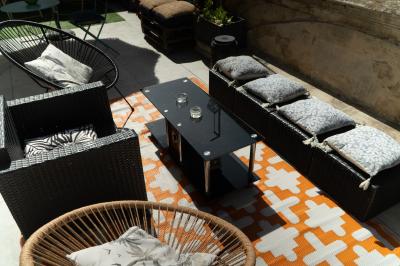 Groupe de personnes discutant et partageant un moment convivial sur une terrasse en soirée, avec des immeubles en arrière…