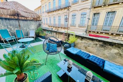 Groupe de personnes discutant et partageant un moment convivial sur une terrasse en soirée, avec des immeubles en arrière…