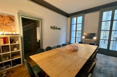 Groupe de personnes discutant et partageant un moment convivial sur une terrasse en soirée, avec des immeubles en arrière…