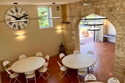 Façade d'un bâtiment en pierre avec de grandes fenêtres, une entrée vitrée et une cour en gravier sous un ciel bleu.