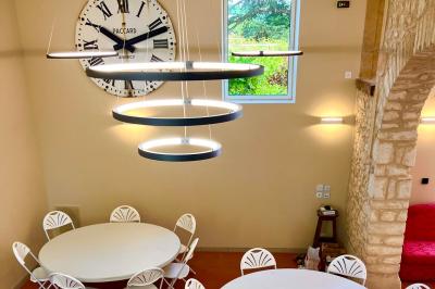 Façade d'un bâtiment en pierre avec de grandes fenêtres, une entrée vitrée et une cour en gravier sous un ciel bleu.