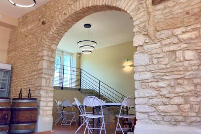 Façade d'un bâtiment en pierre avec de grandes fenêtres, une entrée vitrée et une cour en gravier sous un ciel bleu.