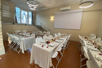 Miniature Location salle Pommiers (Rhône) - Domaine Nicolas Rebut #13 Salle de réception décorée avec des tables rondes dressées, murs en pierre apparente et éclairage chaleureux.