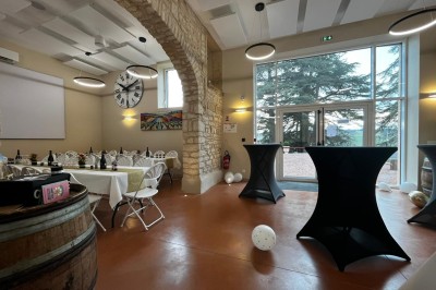 Miniature Location salle Pommiers (Rhône) - Domaine Nicolas Rebut #18 Salle de réception décorée avec des tables rondes dressées, murs en pierre apparente et éclairage chaleureux.