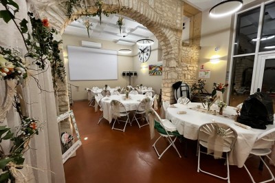Miniature Location salle Pommiers (Rhône) - Domaine Nicolas Rebut #11 Salle de réception décorée avec des tables rondes dressées, murs en pierre apparente et éclairage chaleureux.
