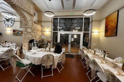 Miniature Location salle Pommiers (Rhône) - Domaine Nicolas Rebut #21 Salle de réception décorée avec des tables rondes dressées, murs en pierre apparente et éclairage chaleureux.
