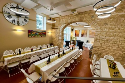 Miniature Location salle Pommiers (Rhône) - Domaine Nicolas Rebut #25 Salle de réception décorée avec des tables rondes dressées, murs en pierre apparente et éclairage chaleureux.