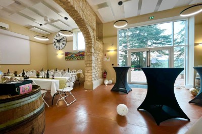 Miniature Location salle Pommiers (Rhône) - Domaine Nicolas Rebut #26 Salle de réception décorée avec des tables rondes dressées, murs en pierre apparente et éclairage chaleureux.