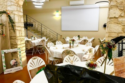 Miniature Location salle Pommiers (Rhône) - Domaine Nicolas Rebut #27 Salle de réception décorée avec des tables rondes dressées, murs en pierre apparente et éclairage chaleureux.