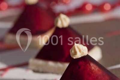 Glycine en fleurs grimpant sur une pergola, avec une maison en briques et des arbustes en arrière-plan.