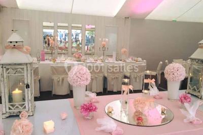 Glycine en fleurs grimpant sur une pergola, avec une maison en briques et des arbustes en arrière-plan.