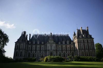 Allée bordée de sacs blancs menant à une tente blanche dans un parc verdoyant par temps ensoleillé.