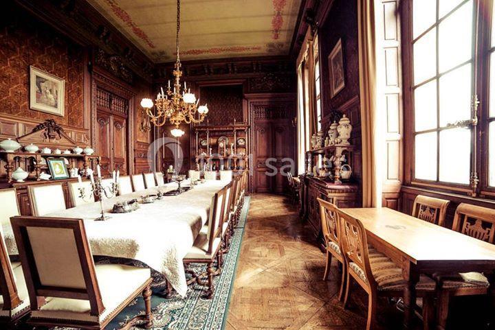 Salle à manger élégante avec une longue table dressée, des chaises en bois, un lustre et une décoration intérieure classique.