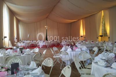 Allée bordée de sacs blancs menant à une tente blanche dans un parc verdoyant par temps ensoleillé.